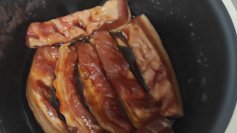 蜜汁五花肉,倒入腌制好的五花肉及腌制用的酱汁(二分之一),盖上电饭锅按煮饭按钮开始褒五花肉。