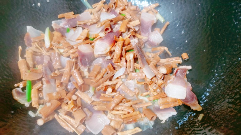 腊肉炒冬笋,接着下入笋干,加入食用盐把它翻炒均匀