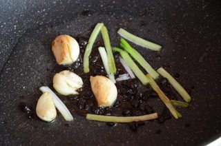 香菇焖鸡腿,炒锅中倒油,放入葱白,蒜和豆豉,小火炒出香味