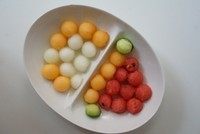 缤纷果球气泡水,将瓜果洗干净,对半切开,用勺子挖去籽和瓤,用挖球器挖出一个个小球。