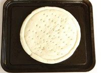 萨拉米肠牛肉披萨,饼坯置干净的烤盘上,并用叉子在饼上叉小洞。