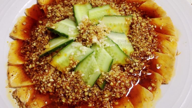 地方菜-蒜泥白肉,将放了蒜末的红油拌匀,并均匀浇在白肉上。