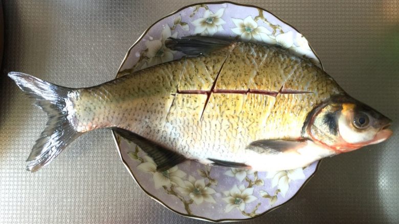 #湖北特色菜#-清蒸武昌鱼,1.新鲜武昌鱼去鳞、去内脏、去腹黑、去鳃,洗净沥干,在鱼身上正反面打花刀。然后在鱼身上、鱼肚均匀抹上适量食用盐,腌渍10分钟。