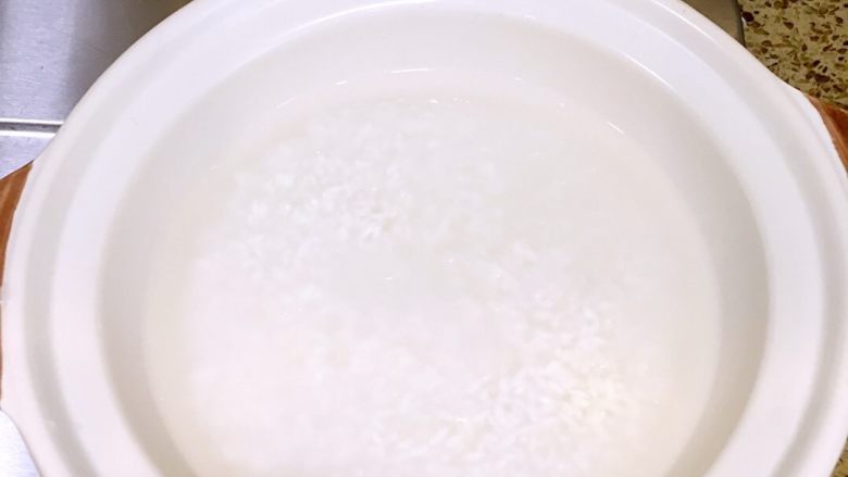 香肠菜花煲仔饭,<a style='color:red;display:inline-block;' href='/shicai/ 513'>香米</a>洗净用纯净水泡15到20分钟,水没过米一点即可,水太多米饭太软影响口感,加一点油搅拌下上锅开大火煮开。