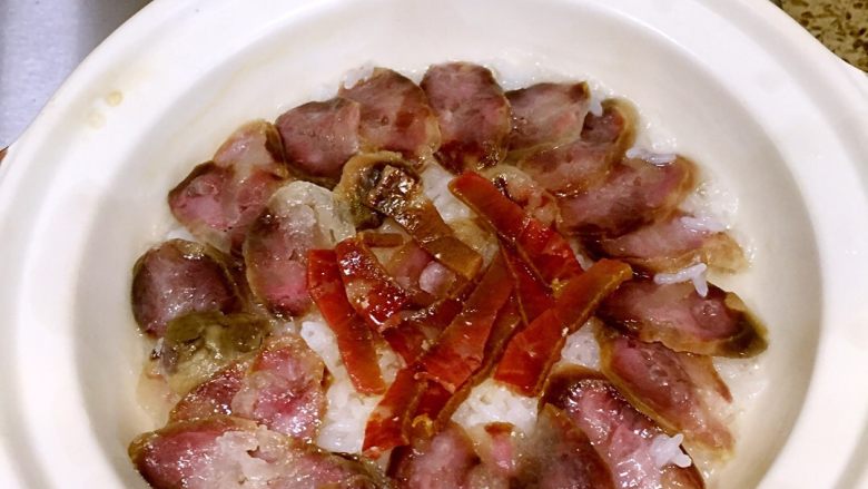 香肠菜花煲仔饭,煮开后把切好的香肠咸肉码在上面,周围淋点油,开中火。
