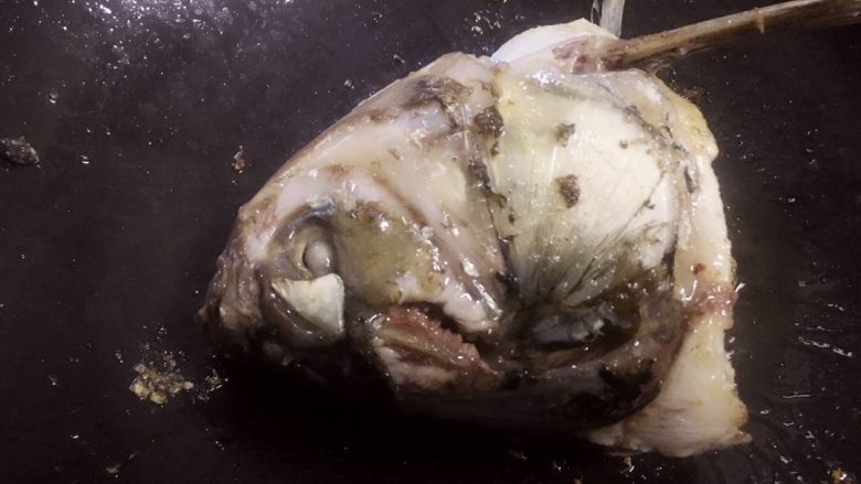 鱼头豆腐汤,锅底用姜片摩擦后,倒入适量油(猪油最佳)。将鱼头两面煎香。