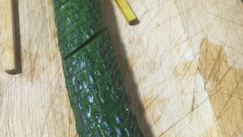 蓑衣黄瓜,斜切片、不要完全切断深度最好一致、技术不好可用2根筷子垫上,黄瓜两侧各摆一根、刀切到筷子就停下,