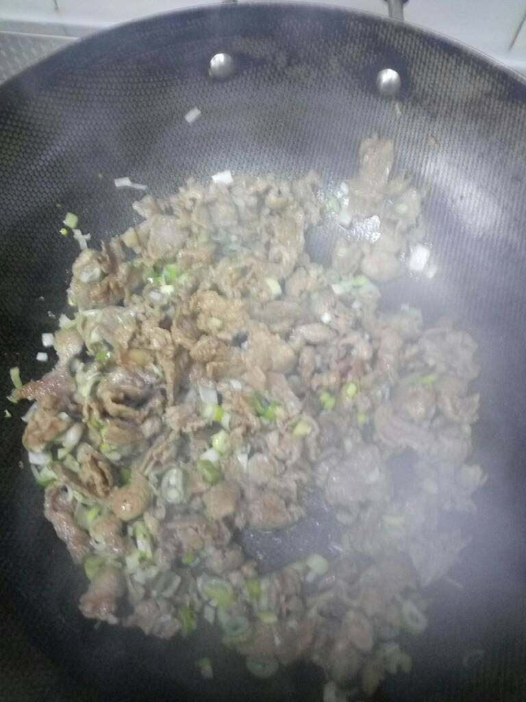 创新版馕包肉,看到锅中水分不多了,几乎炒干了时加入大葱丁,再加入适量的盐,因为这个菜有其他香料,所以不用加很多的盐
