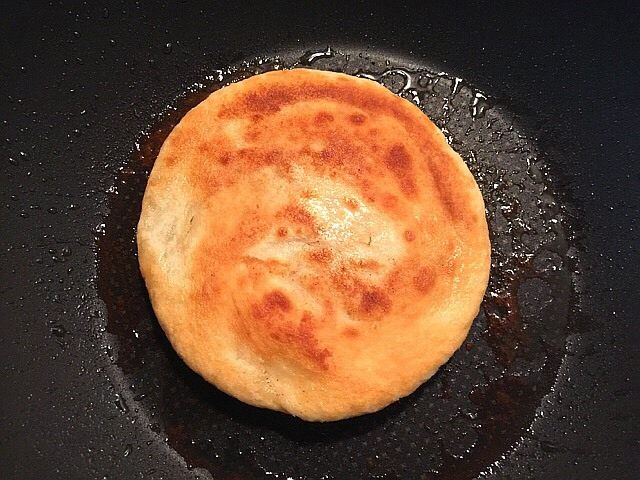 家常椒盐发面饼,锅内放油中火下锅,一面烙至金黄后翻面再烙。膨胀变大变厚后就可以出锅了。