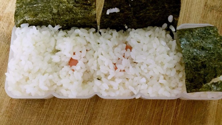 火腿芝士夹心手握,盖一层米饭,压实。