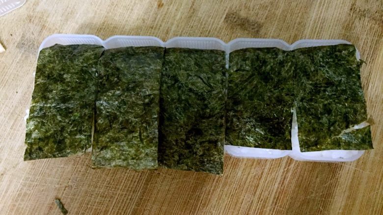 火腿芝士夹心手握,把上层海苔盖在米饭上。