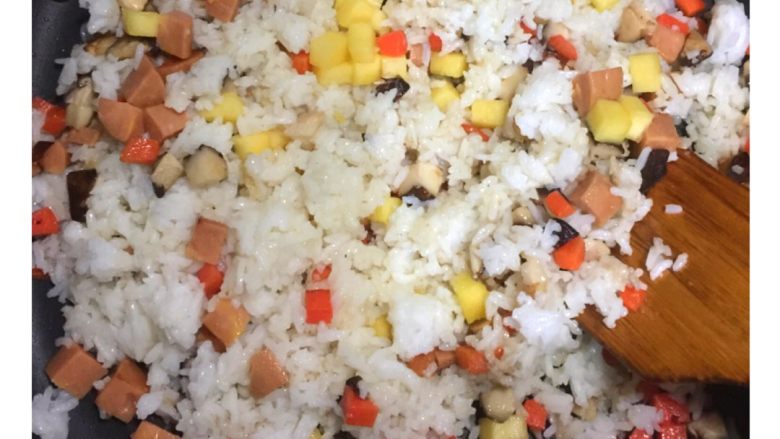 五彩扬州炒饭#健康美颜餐#,锅内加入白米饭、玉米热狗肠粒、菠萝粒翻炒,待米粒松散。