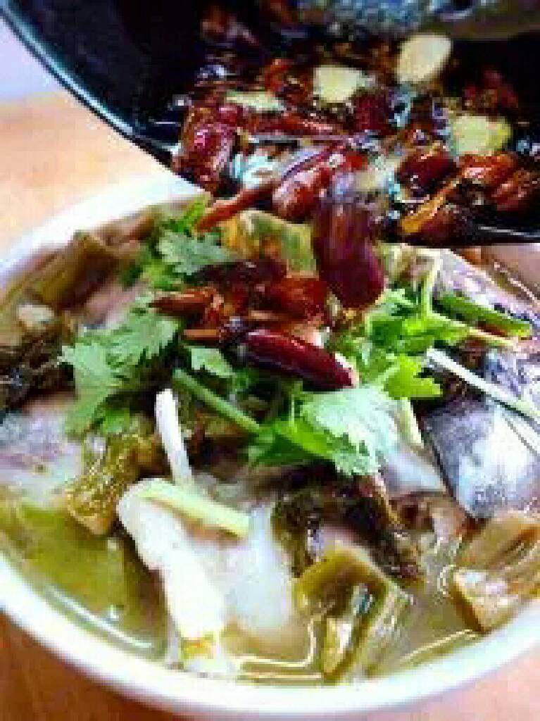 江湖酸菜鱼,炒锅中加入适量的油,温油加入干红辣椒、蒜片、花椒麻椒,炸至干红辣椒变酥脆后,趁热倒在做好的酸菜鱼表面即可