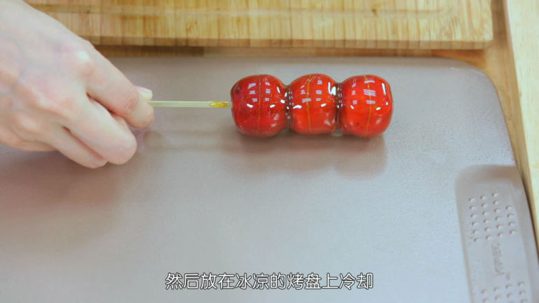 冰糖葫芦,裹好糖浆之后把糖葫芦放在处理好的烤盘上面冷却成型,最少冷却10分钟再食用,糖浆如果在裹的过程中变稠了,我们可以小火加热一下恢复流动性继续裹,直到我们明显觉得裹的糖变厚了,糖浆变成焦糖色,就不要再裹了