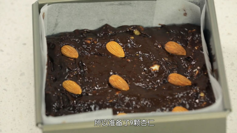 布朗尼,模具铺上油纸,把布朗尼面糊倒入模具中铺平,然后放上整颗的杏仁和杏仁碎,面糊就做好了