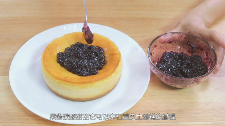 烤蓝莓重芝士蛋糕,重芝士蛋糕冷藏完之后我们脱模把它移到碟子上,小心不要把饼干底铲碎了,蓝莓果酱完全冷却之后会结块,我们需要用勺子把它混匀一下,这样才可以铺在重芝士蛋糕上,把搅拌过后的蓝莓果酱铺在重芝士蛋糕上面,那这个蓝莓重芝士蛋糕就做好喽