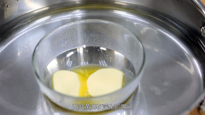 蓝莓益力多慕斯,首先把无盐黄油隔水溶化成液体,黄油在溶化期间,我们把消化饼干用料理机打成粉末,然后倒出来,没有料理机的朋友可以参考《草莓芝士慕斯》中饼干底的做法