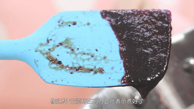 蓝莓益力多慕斯,蓝莓果酱煮沸之后马上转中小火,挥发一些水分,把蓝莓果酱煮稠,煮到刮刀上的状态就可以了,成品出来大概是120克左右,然后把煮好的果酱倒出来碗里放凉备用