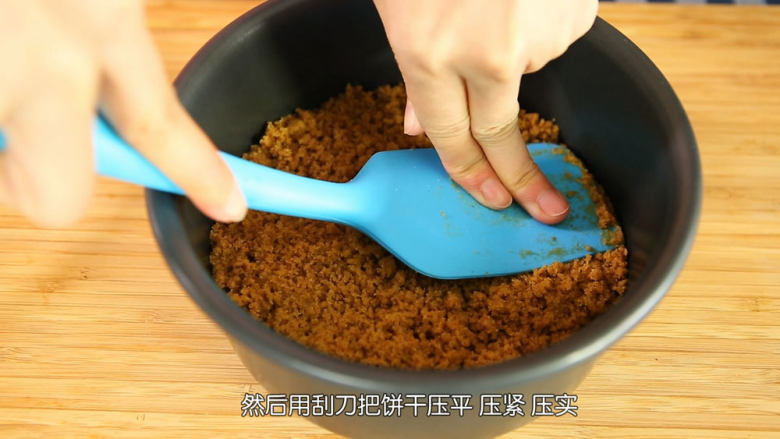 芒果流心慕斯,把和无盐黄油混合好的饼干碎倒入模具中,用刮刀压平压紧压实,然后放入冰箱里面冷藏,一定要压实,不压实,脱模切件的时候很容易会散掉