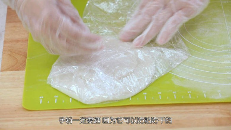 雪媚娘大福,每擀好一张面皮之后在表面抹上一点手粉防粘,然后叠在一起,放在保鲜膜上面,再用保鲜膜包好,防止皮干掉,皮干掉就会变硬,包不起来了,手粉一定要撒,因为它可以防粘和防干哦,包之前把所有面皮都擀好备用,因为待会要包淡奶油,淡奶油比较容易化