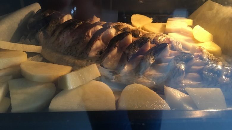 豆豉风味烤鱼,五分钟后,先把土豆片铺在鱼的周围,土豆片不太容易熟,所以要比别的菜先放,继续烤15分钟。这一步可以再刷一遍料油,包括土豆。其实这一步土豆和鱼一起放也可以,我怕太熟不成形,我做的土豆还稍稍有点硬。