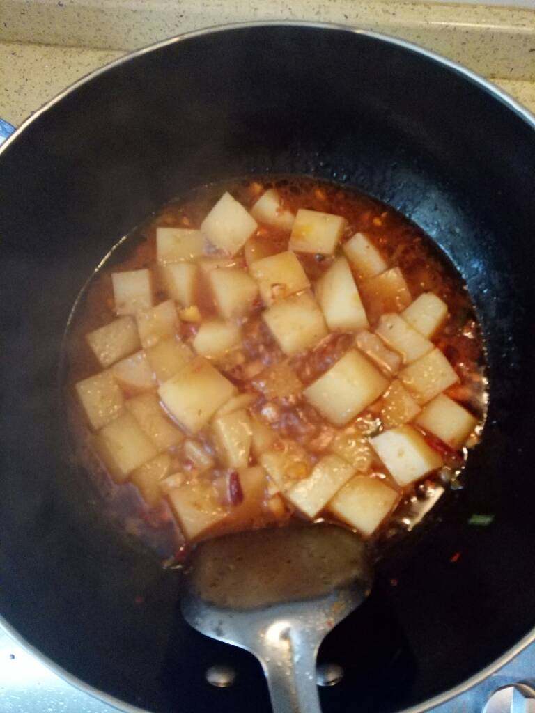 麻辣米豆腐,锅里汤汁烧开后,开小火,放入花椒面,葱花,翻炒几下,关火,加入鸡精翻炒,即可出锅