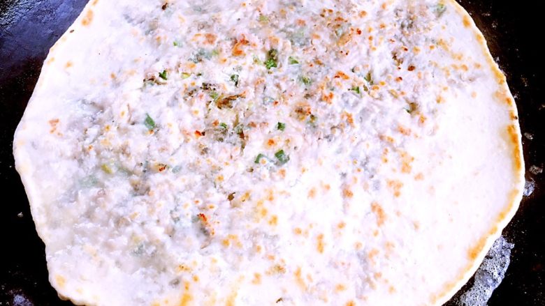 梅干菜猪肉麦饼,待薄饼烙略金黄时翻面,刷油,撒几滴水盖锅盖约一分钟左右。
