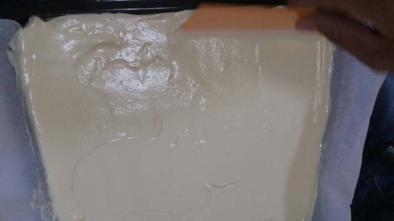 奶油草莓蛋糕卷,把面糊倒入铺了油纸的烤盘,抹平,并用力地震几下,让面糊内部的大汽泡跑出来。