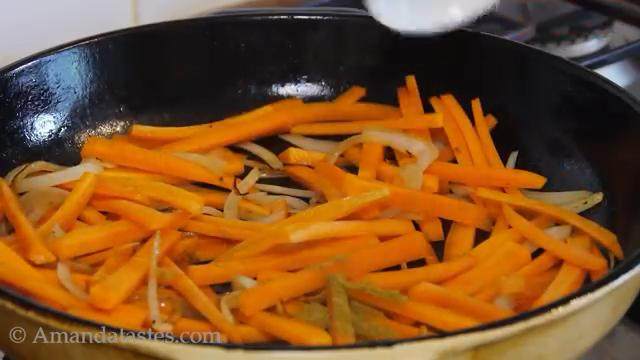 羊肉抓饭,倒入洋葱翻炒至焦黄，倒入胡萝卜、孜然粉翻炒