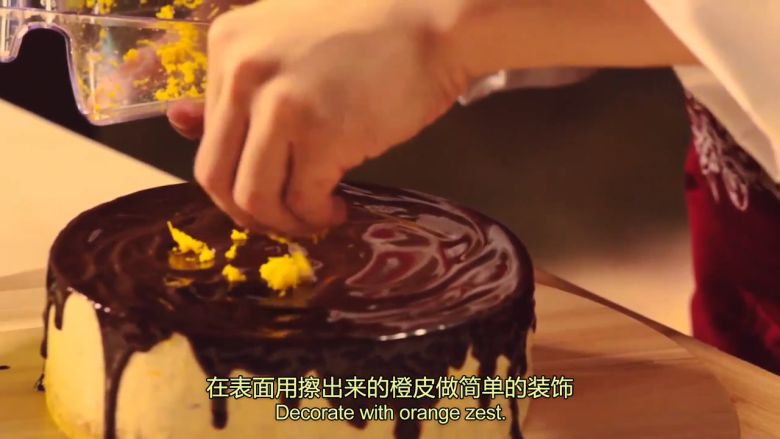 橙香米蛋糕,蛋糕从冰箱取出脱模,散热,淋上巧克力甘纳许,再用橙皮做简单装饰