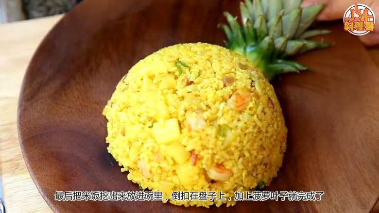 菠萝咖喱炒饭【134版】,烤好后将饭挖出来,放进碗里,倒扣在盘子上然后摆上菠萝叶即可