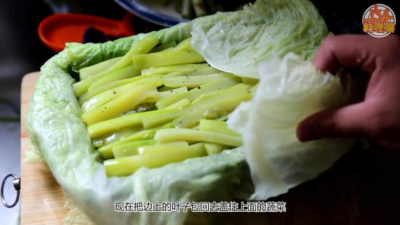 九珍蔬菜法式冻,把铺出来的叶子往里包盖住上面的蔬菜,再包上保鲜膜,最后盖上一张保鲜膜,盖上竹帘,压上重物,最后放冰箱冷藏
