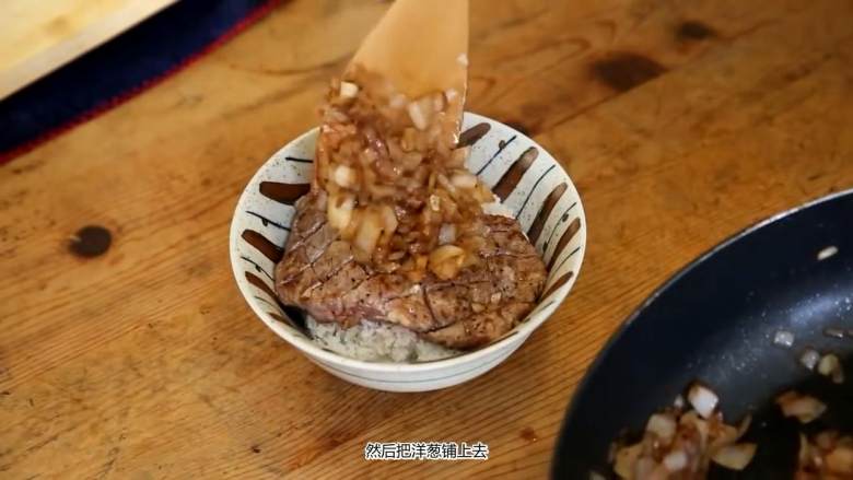 夏里亚宾牛排丼,盛一碗饭，放上牛排，再倒上洋葱，撒一点葱花装饰
