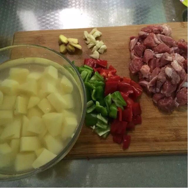 土豆烧牛肉,食材洗净,牛肉用水多泡一会儿泡出血水后切块,土豆去皮切块,青红辣椒切块,蒜拍碎,姜切片
