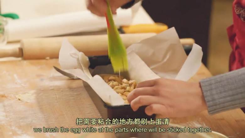 肉桂苹果派,把面皮和油纸一起放入模具,把黄油面包屑铺在底部,加入拌好的苹果馅料,在需要粘合的地方刷上蛋清