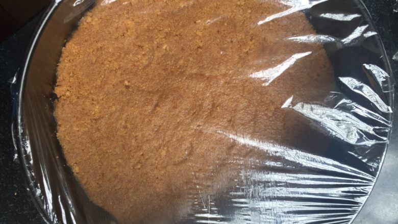 樱花芝士蛋糕(8寸带有镜面层免烤版),这一步就更简单了,把搅拌均匀的黄油和饼干一起倒入8寸的活模里,然后用工具按实拍平,一定要按实啊,还有弄平整一点,不会显得蛋糕整体都是歪斜着。弄好之后加一层保鲜膜放入冰箱里冷藏,等待备用。