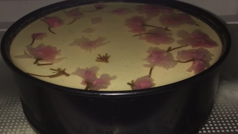 樱花芝士蛋糕(8寸带有镜面层免烤版),第二天早上,先是用4片5克左右的吉利丁片放入冷水等待泡软备用,然后找一个搅拌盆倒入400ml的雪碧,再把已经泡软沥干的吉利丁片放在雪碧里,可以加白砂糖10g也可以不加白砂糖,这就是为什么我在写材料的时候白砂糖写的是80g~90g了。加糖是为了镜面层甜更像果冻一样,在雪碧气味里更有味道,不加也没事,味道不会很甜罢了!然后隔着热水一个方向搅拌至吉利丁片消失不见即可,放在旁边放凉等待使用即可,然后从冰箱里取出前一天做好的芝士层,把放凉的雪碧吉利丁片混合液慢慢倒入芝士蛋糕模里,再把已经泡好的樱花用牙签按照自己喜欢的样子放入模具里就可以了,因为放樱花没有什么规律可言,所以随心就可以了!只要你摆的好看就行,不要太密否则真的很难看!我是早上五点起来弄的,只用了10多分钟就摆好了所以直接又放在冰箱冷藏里,然后洗手出去晨运,不耽误事儿!