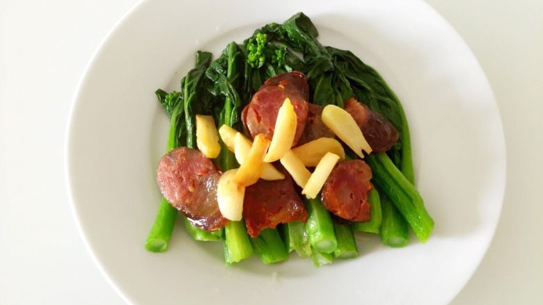 腊肠炒菜心,热锅冷油，放入腊肠煎一下，然后放入蒜瓣，再放菜心一起炒，炒至菜心快熟，撒少许盐，炒匀即可出锅装盘。