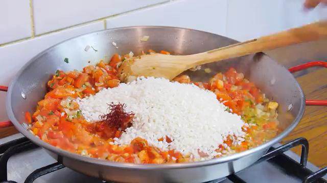 西班牙海鲜饭,撒入红椒粉，再倒入米和藏红花翻炒