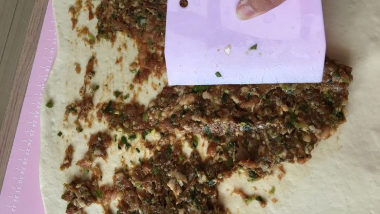 肉肉的大懒龙-肉卷,将调好的肉馅分出一半,到在面片上,用刮板刮匀。