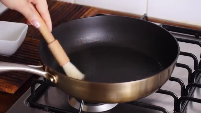 抹茶千层蛋糕,找一口平底不粘锅,开小火预热一会儿,准备一小碟油和一个刷子,在锅底薄薄地刷上一层油