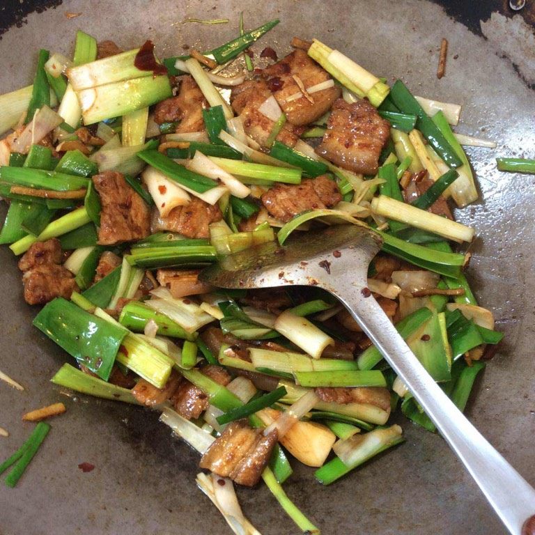 回锅肉,再洒入一茶匙清水翻炒后放入青蒜,翻炒至青蒜断生完工。