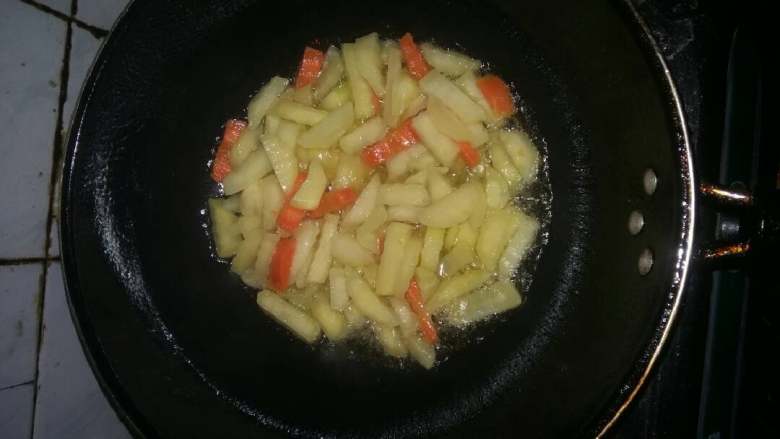 狼牙土豆条,锅烧热倒入色拉油5成热,倒入土豆条和胡萝卜条煸炒。