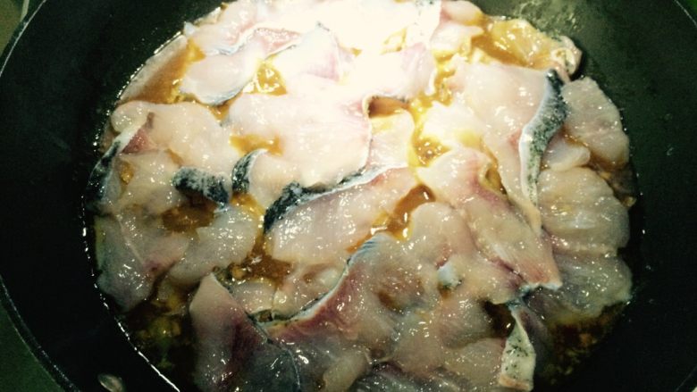 麻辣风味花莲鱼,等锅中鱼骨类烧至八成熟后,调小火,在鱼骨表面放腌好的鱼肉片(一片一片平放)。