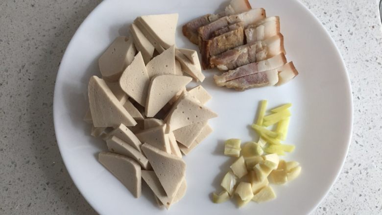 小炒千叶豆腐,先将<a style='color:red;display:inline-block;' href='/shicai/ 436'>腊肉</a>切成小片，豆腐切片，蒜切片，<a style='color:red;display:inline-block;' href='/shicai/ 37'>姜</a>切丝备用