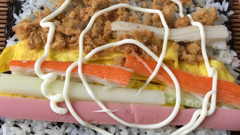 寿司,然后把准备的材料铺在糯米上面,挤上沙拉酱、就可以开始卷了,一定要卷紧。
