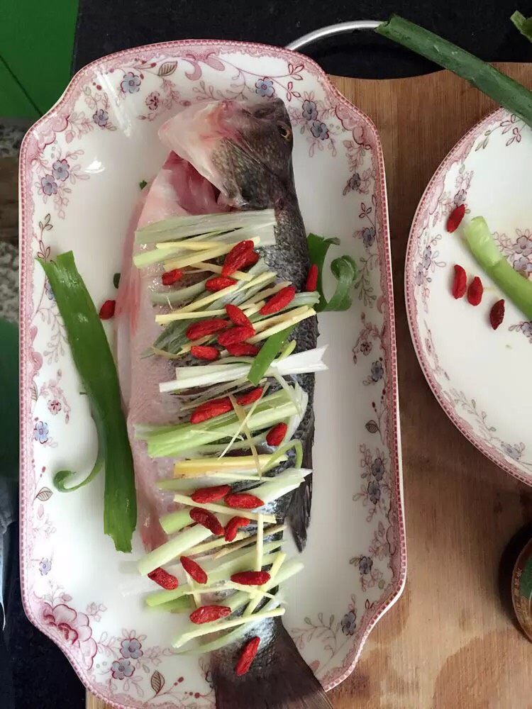 清蒸鲈鱼,鱼放入盘,在鱼上面摆上葱姜丝、枸杞,鱼旁边也可以摆放点葱