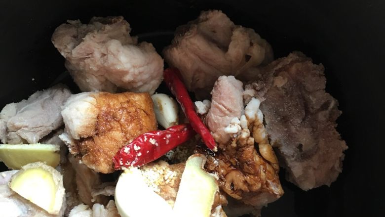 高压锅土豆炖排骨,洗干净的排骨放在高压锅内胆里,撒入盐,料酒生抽,老抽,鸡精,生姜片,辣椒干拌匀,腌制十五分钟