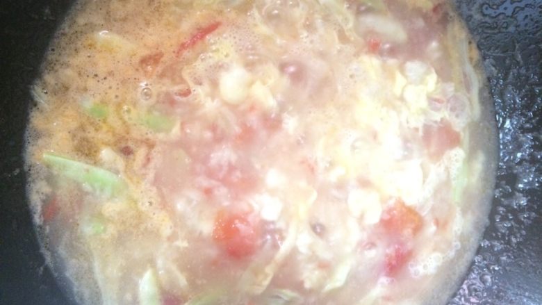 西红柿鸡蛋疙瘩汤,用筷子比住碗,把鸡蛋倒入锅中(拿勺子趁一下锅底,以防止沾锅)