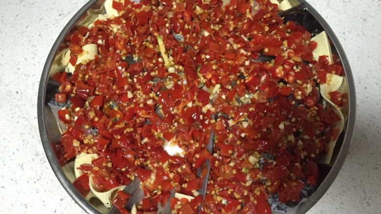 剁椒鱼头,把姜片和葱段铺在盘底,上面铺上烫洗好的豆皮,然后上面放入腌制好的鱼头,再把拌好的剁椒均匀的铺在鱼头上面。